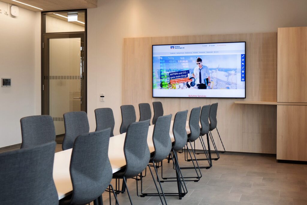 Digitale Signage (Display) in einem länglichen Meetingraum der Volksbank Memmingen eG