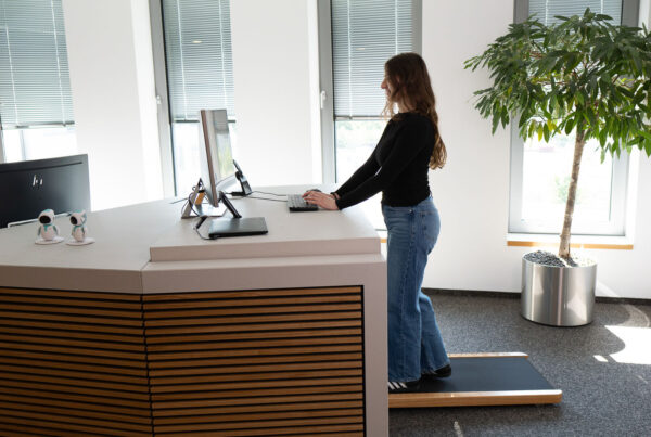 Person in einem Büro auf einem Laufband, die an einem Schreibtisch arbeitet.