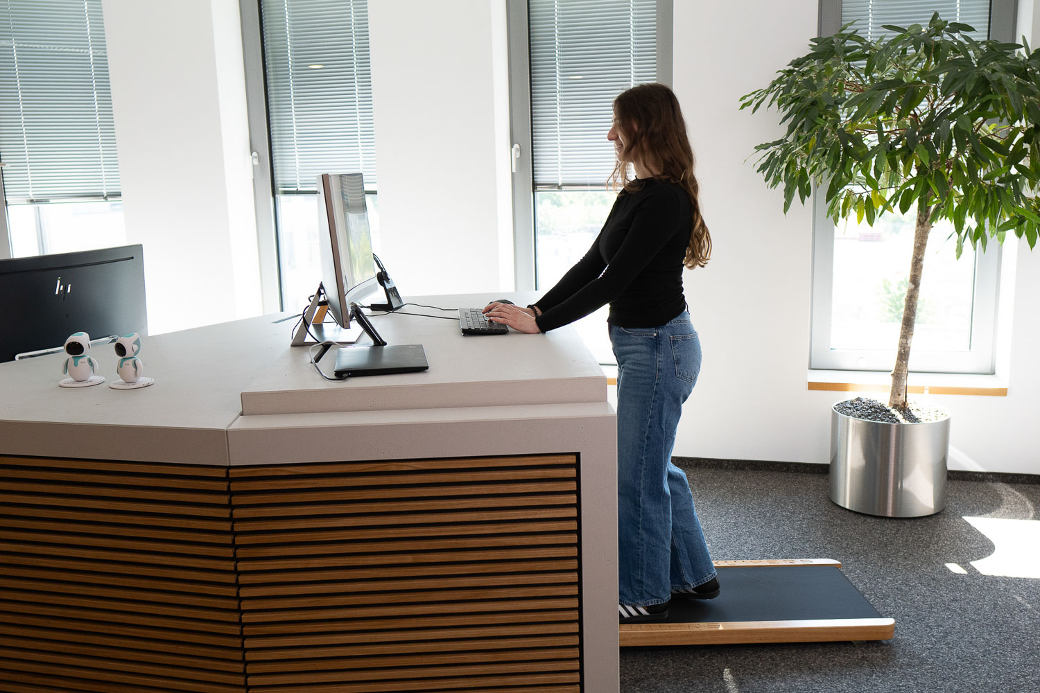 Person in einem Büro auf einem Laufband, die an einem Schreibtisch arbeitet.